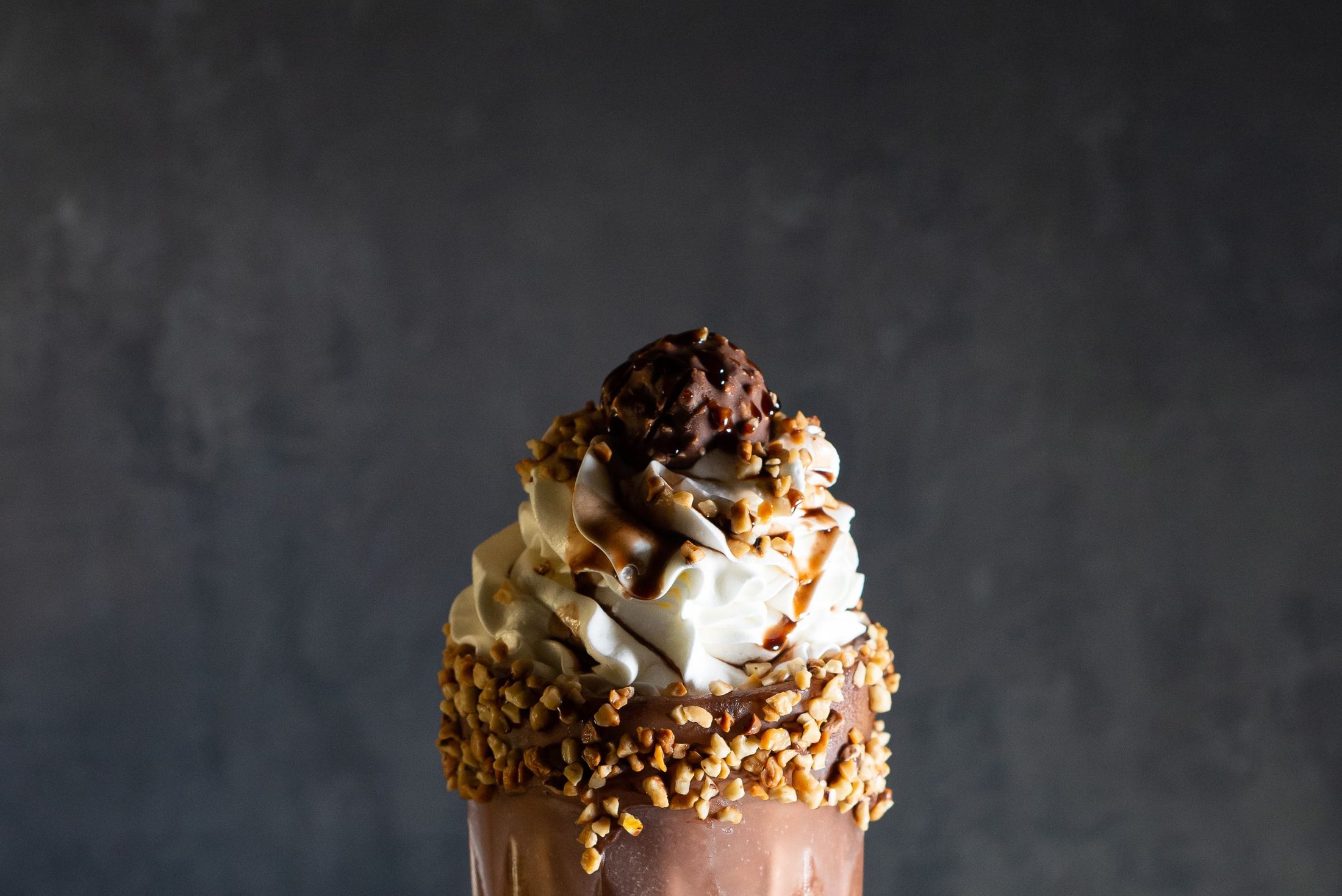 A thick shake crowned with cream, lit against the dark